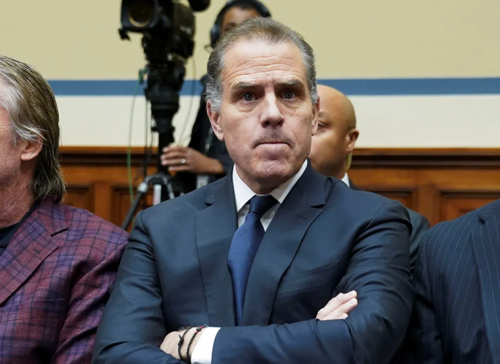 Hunter Biden sitting in congressional hearing, looking stern with arms crossed.